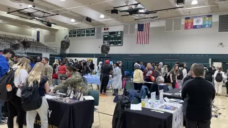 many people standing in a large room with display tables
